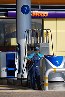 Fuel Attendant at a Sasol Station with FRP Infrastructure – A fuel attendant servicing vehicles at a modern fuel station with FRP-clad pumps, hose organizers, and litter bins for a streamlined experience.