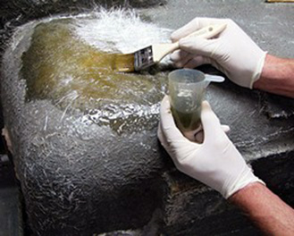 Worker applying resin to fiberglass during the FRP lamination process on steel machinery